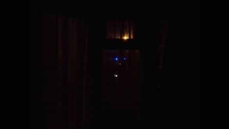 luces de emergencia azules intermitentes vistas a través de las cortinas por la noche