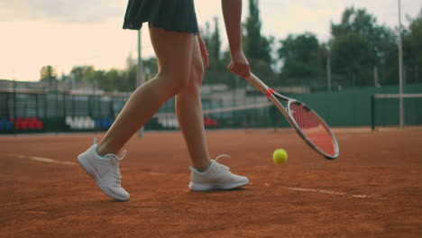 slow-motion side view of a young athlete trains the serve of the tennis ball. a teenage athlete is playing tennis on a court. an active girl is powerfully hitting a ball during sport practicing