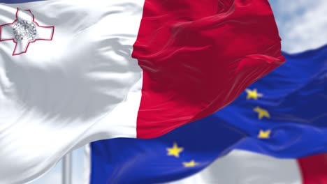 detail of the national flag of malta waving in the wind with blurred european union flag in the background