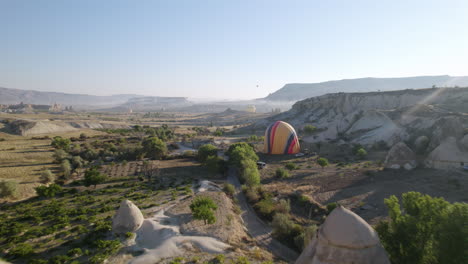 hot air balloon getting deflated after flying over hills during sunset in cappadocia