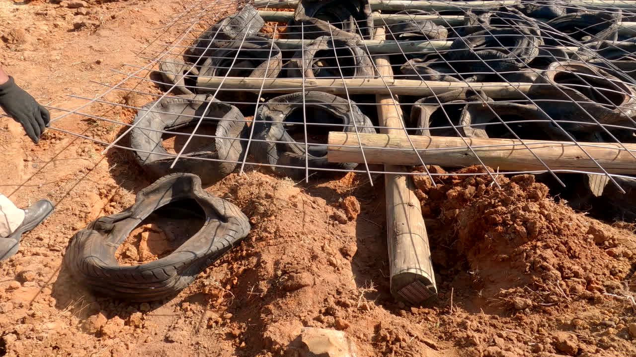 los empleados agrícolas en áfrica usan neumáticos de automóviles reciclados y postes de árboles de goma para detener la erosión, mostrando técnicas agrícolas innovadoras y sostenibles en áreas rurales periféricas