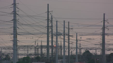 static shot of steel posts and power lines with body of water in the background