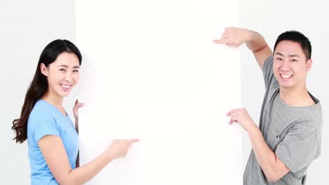 보드를 가리키는 미소 짓는 부부
