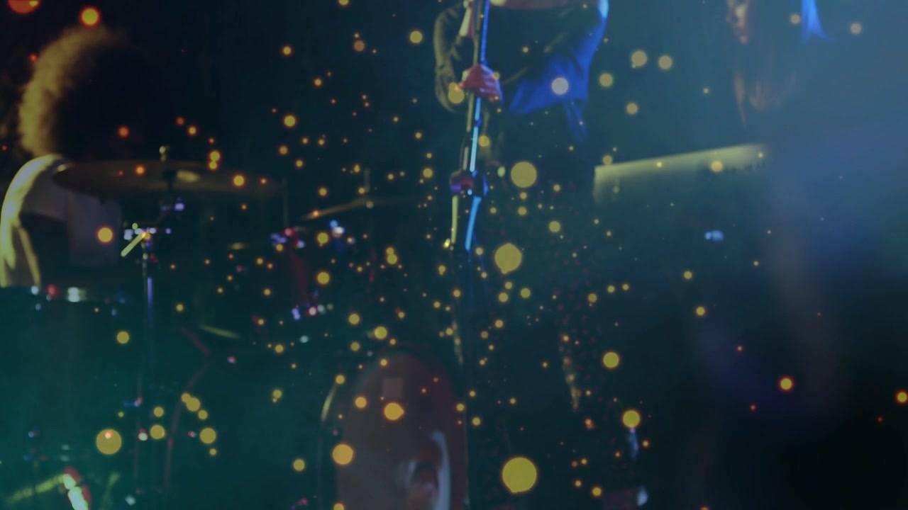 Vertical video: Golden particle shifting, revealing band playing with mic and drums, creating mood