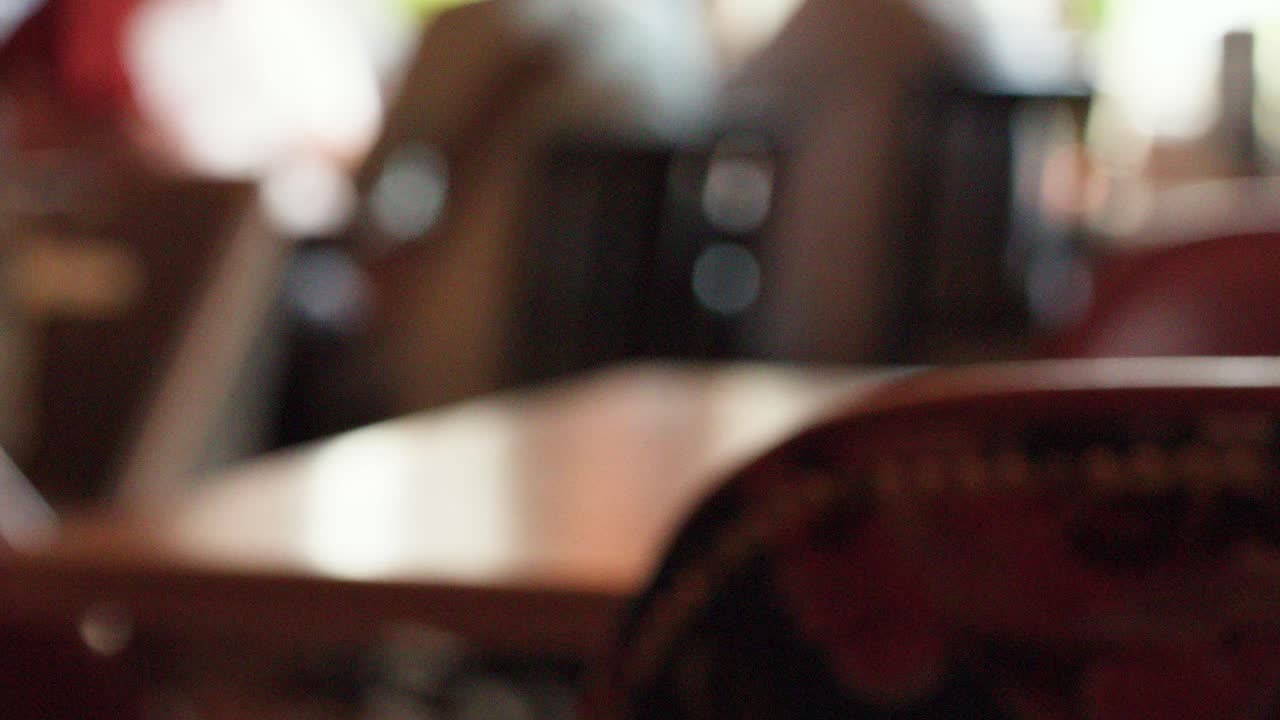 A pint of dark beer lifted from a pub table, background blurred with warm lighting