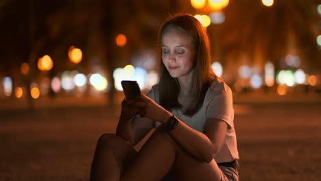 Una-Hermosa-Joven-En-Verano-En-Una-Gran-Ciudad-Nocturna-Mantiene-Un-Teléfono-Inteligente-En-Su-Interior-Y-Escribe-Un-Mensaje-Lee-Correos-Electrónicos-Y-Se-Comunica-En-Salas-De-Chat-Y-Redes-Sociales-Mantiene-Un-Blog-Mira-La-Pantalla-Del-Teléfono