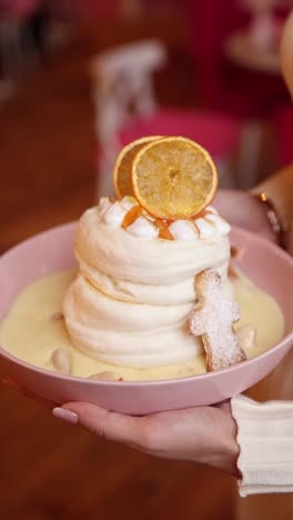 woman holding a beautiful dessert with meringue, custard and orange slices