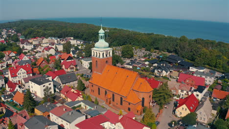 Vista-Aérea-De-La-Iglesia-En-Jastarnia,-Polonia-Con-El-Mar-Báltico-Al-Fondo.