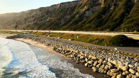 Aerial-pull-back-shot-revealing-the-beach,-mountains,-and-PCH-in-California