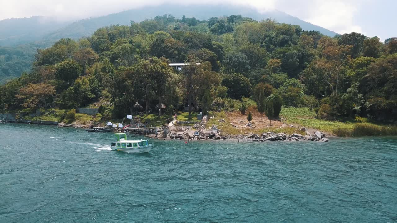 Drone aerial view, boat driving over the lake and the dock in Lake Atitlan, Guatemala