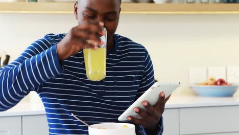 Man-using-a-digital-tablet-while-having-juice