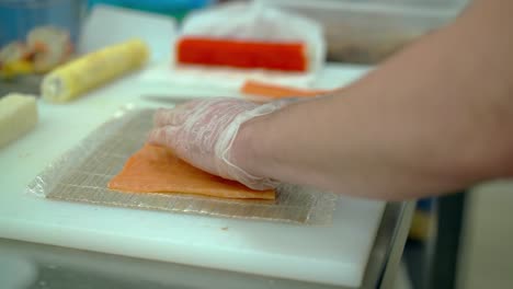 cook prepares slices of salmon for sushi