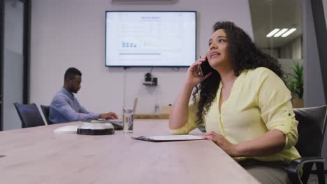 Happy-diverse-couple-of-business-people-working-together,-talking-on-smartphone-in-modern-office