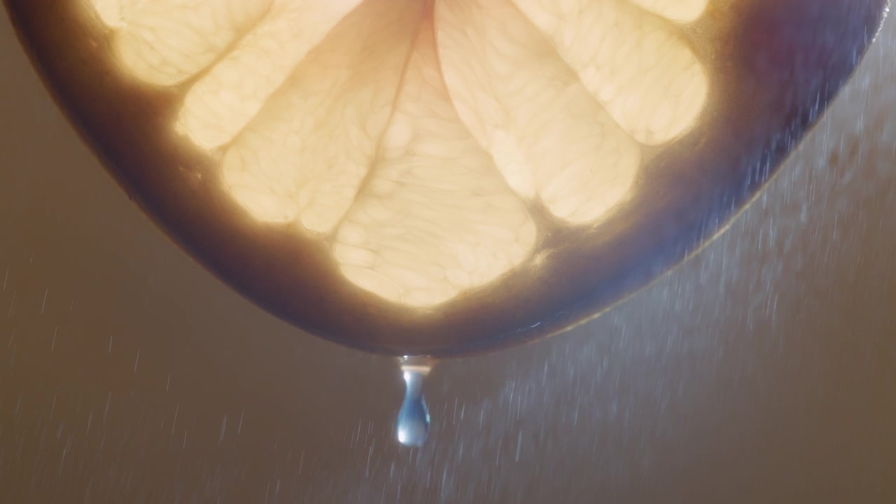 Gocce d'acqua che cadono da una fetta di pomelo bianco, con spruzzi d'acqua sullo sfondo.