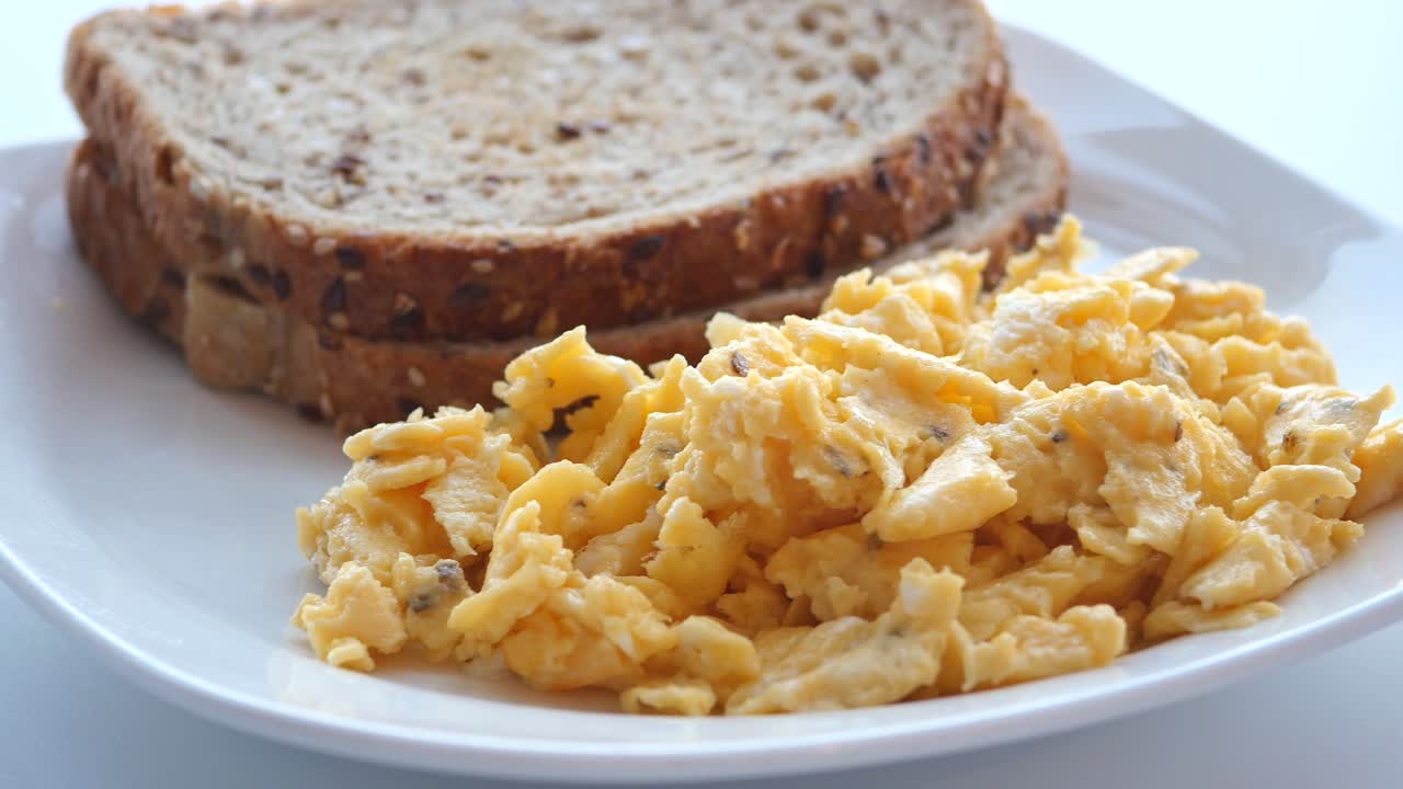 Scrambled eggs on a bread on white plate