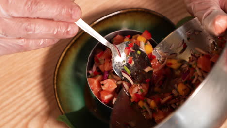 tuna ceviche - tuna tartare - chef pouring the seasoned and mixed raw tuna with chopped vegetables on a stainless molder