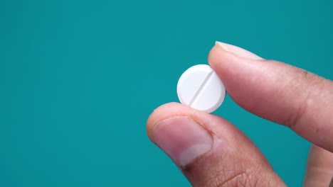 a hand holding a white pill