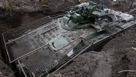 modern russian armor in ukraine: this is a bmd-4m fighting vehicle in a dug-in position, equipped with a field-modified 'cope cage' to protect it from kamikaze drones
