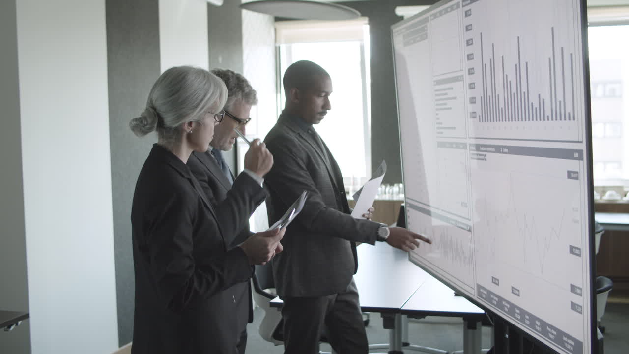 Business experts analyzing data on screen