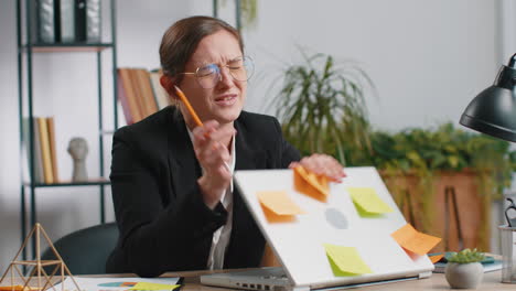 tired sad exhausted businesswoman working on laptop at office with many sticker tasks, panic attack