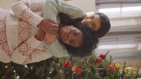 portrait of joyous african american mom and daughter by christmas tree