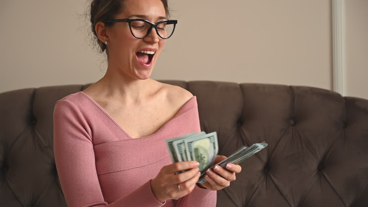 Smiling woman counting multiple one hundred dollar bills in her hands