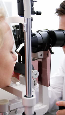 optometrist examining female patient on slit lamp