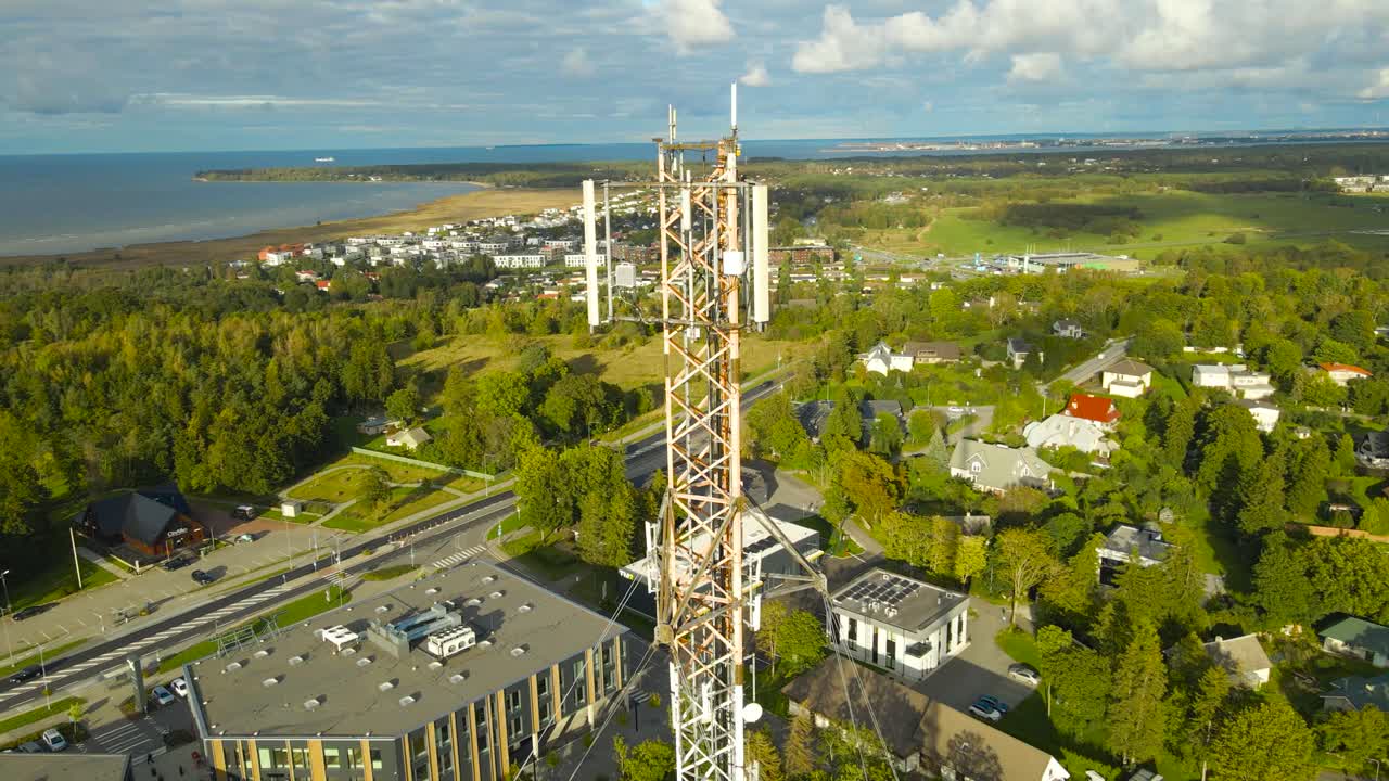 Aerial drone footage orbiting and flying around a large modern radio or tv network broadcasting tower with 4G, 5G and even 6G vidgets and technology mounted on it during a sunny summer day in horizon
