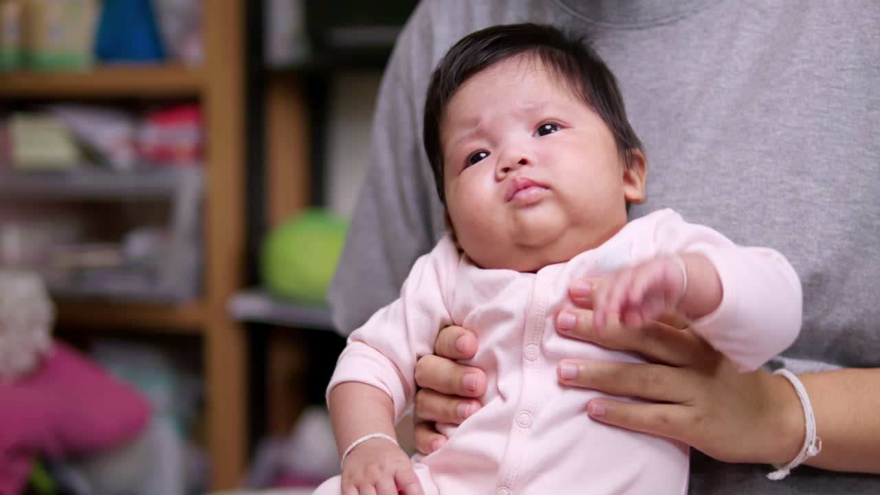 엄마의 무에 앉아 있는 신생아는 팔을 흔들면서 걱거리고 울기 시작한다.