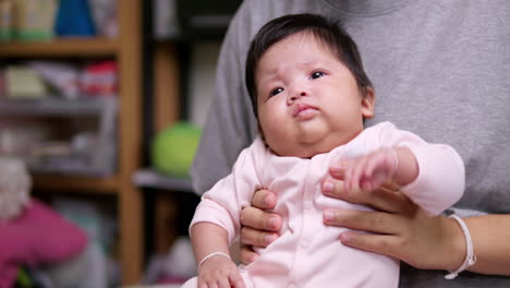 sentada en el regazo de su madre, una niña recién nacida comienza a retorcerse y a llorar mientras agita sus brazos