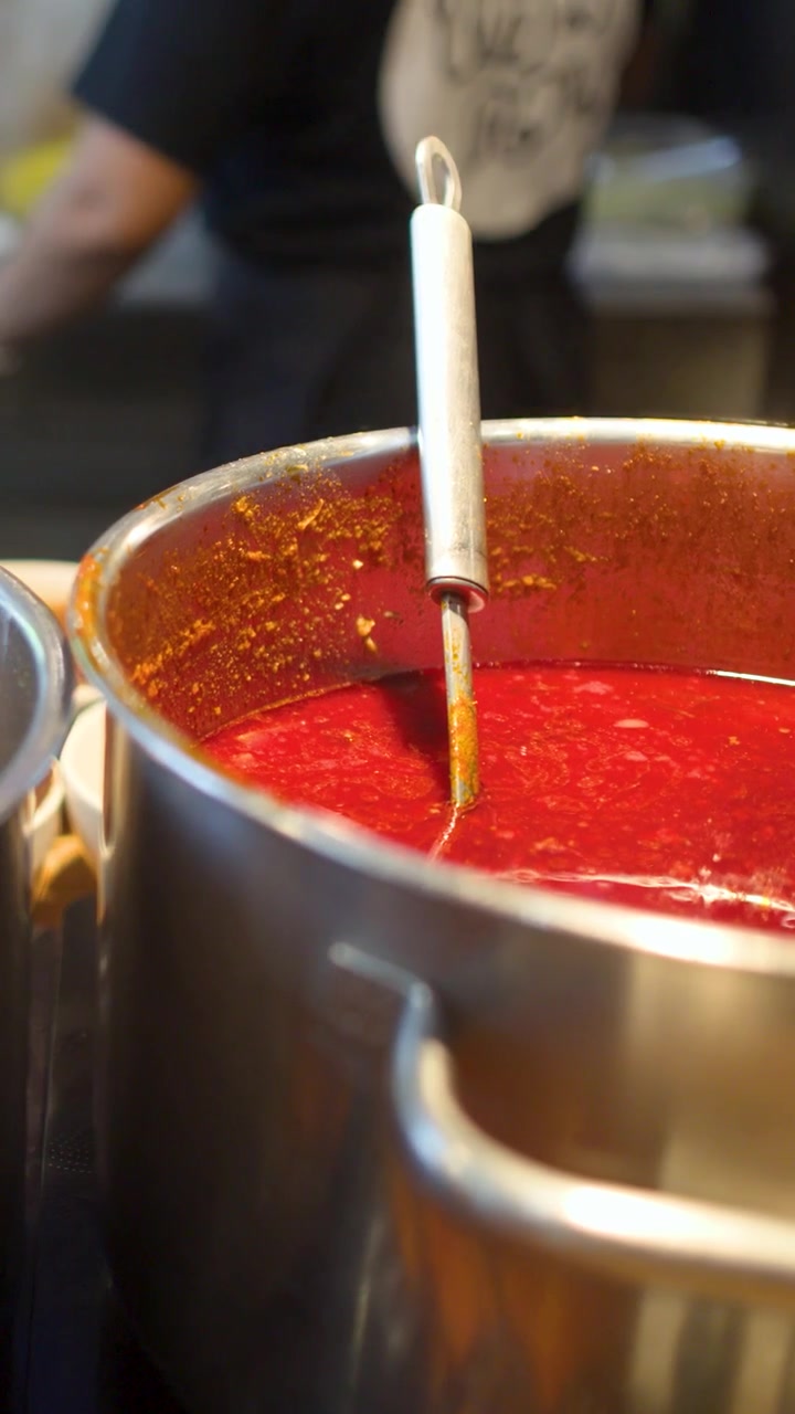 Primo piano di grandi pentole di metallo contenenti curry rosso e stufato di verdure a Bangkok.