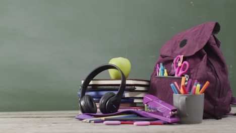 video de suministros escolares y libros en una mesa de madera sobre una pizarra