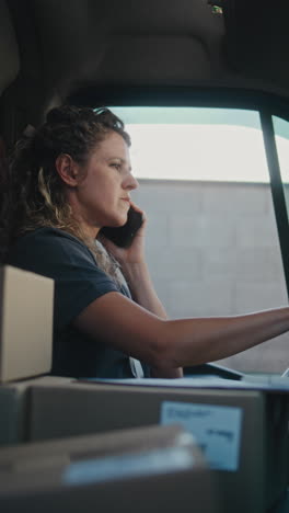 woman working in a delivery van, handling calls and paperwork