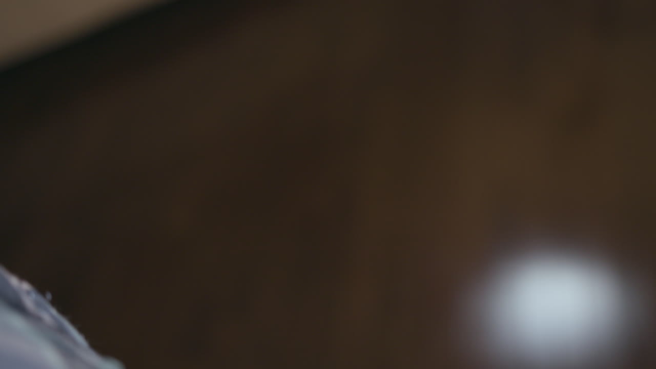 Over the shoulder shot of a hand raising a pocket watch into frame, opening it, and closing it