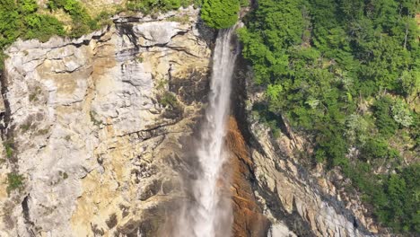 waterfall drops from dense green forest into rocky cliff near klöntalersee