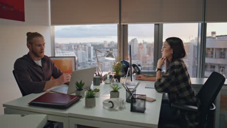 two people brainstorming at sunset view office close up. colleagues discussing