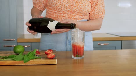 woman making cocktail drinks at home kitchen.drinks and people concept  young woman making strawberry mojito cocktail at home kitchen