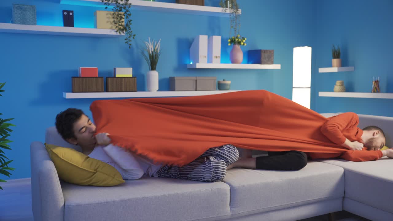 두 형제가 집에서 담요를 놓고 논쟁하고 있습니다.