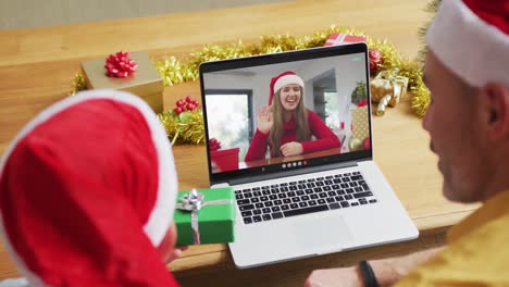 Caucasian-father-with-son-using-laptop-for-christmas-video-call,-with-smiling-friend-on-screen