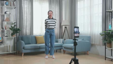 young woman doing a video call and dancing in her living room