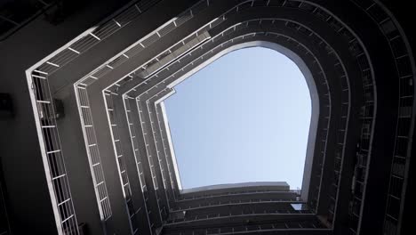 a bottom perspective of rounded shaped building. real estate. modern building construction. external view. architecture scene. spiraling structure. swirling up to sky