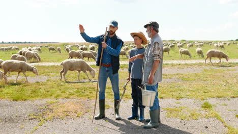 caucasian grandfather, father and son talking at a green field