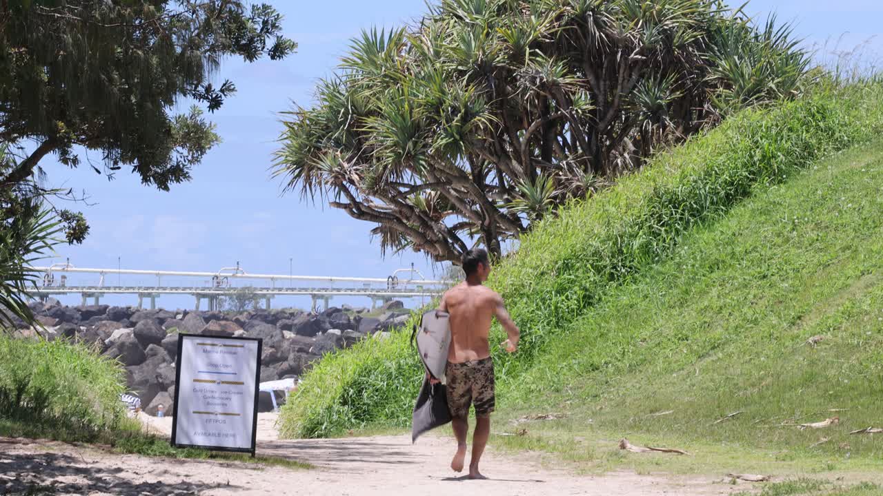한 남자가 바다 근처의 정보 표지판을 지나간다