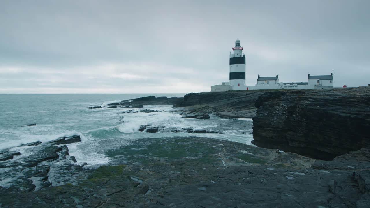 슬로우 모션으로 해안선에 있는 검은 절벽 근처의 등대