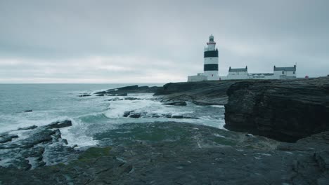 Lighthouse-near-black-cliffs-on-the-shoreline-in-slow-motion