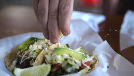 slow motion closeup of squeezing lime on traditional tacos