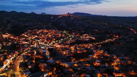 aerial view of illuminated town at dusk with mountains in background