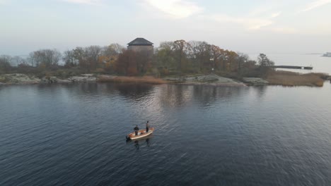 two fishermen standing on their boat trying to catch some fish in the beautiful archipelago in the naval city of karlskrona, sweden