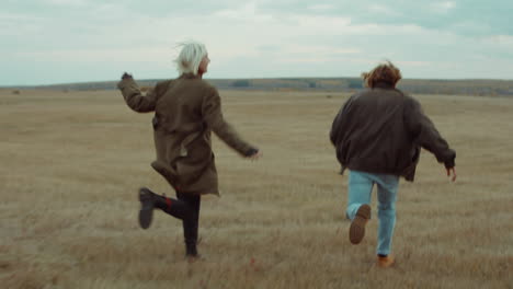 carefree couple running through autumn field