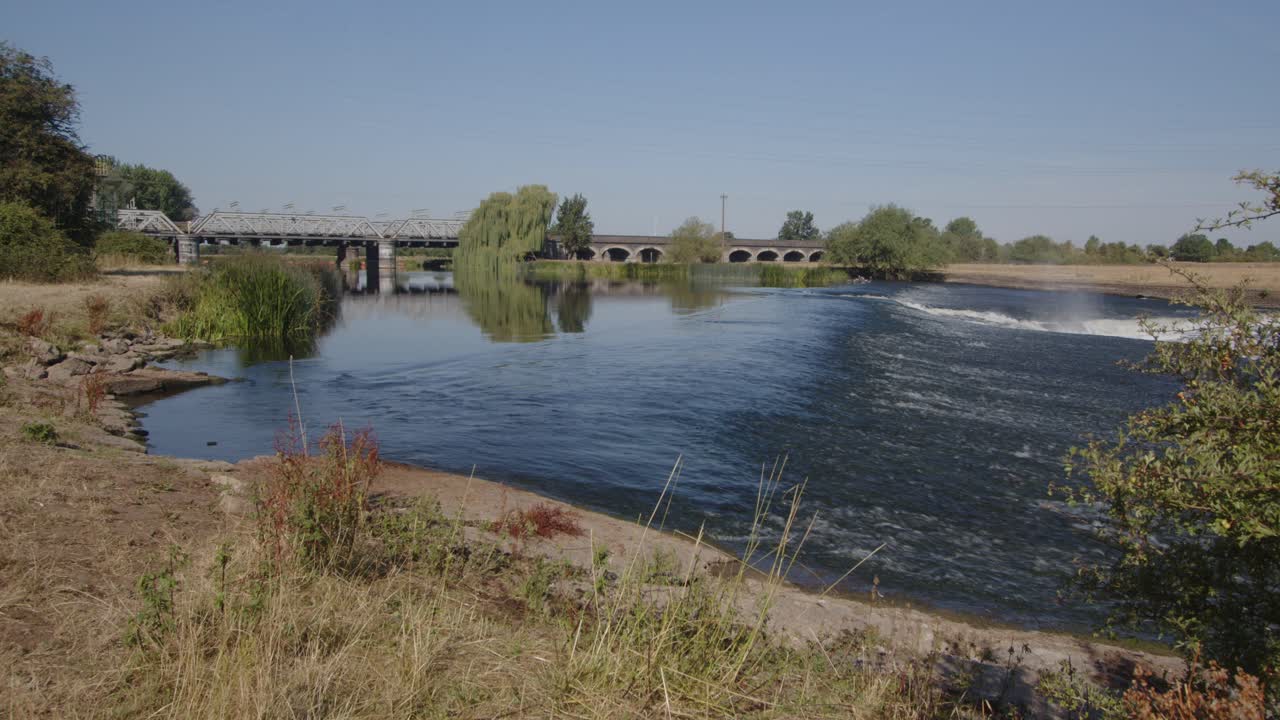 River Trent weir with the Trent Railway line bridge in background, by Ratcliffe on Soar Power station. Wide shot